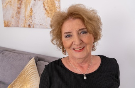 Granny Noretta shows her black panties & stockings while posing on the sofa