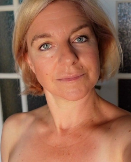 Blue-eyed mature blonde flaunts her hot curvy body while posing in the window