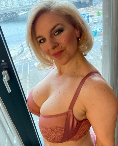 Blue-eyed mature blonde flaunts her hot curvy body while posing in the window